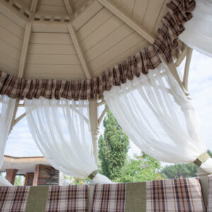 White tulle curtains with a checkered border and pillows in the gazebo - textiles Wood Luxury.