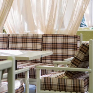 Green summer cafe furniture with checkered pillows and white curtains - project Wood Luxury.